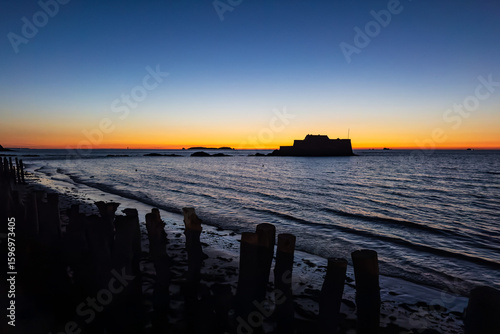 Fortress at Sea – Coastal Silhouette at Sunset with Wooden Groynes