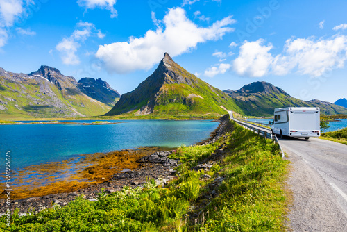 FREDVANG, NORWAY - JUN 26, 2025: Camper car driving on road over Fredvang bridge and view of sea and Volandstinden mountain, Lofoten Islands, Norway.