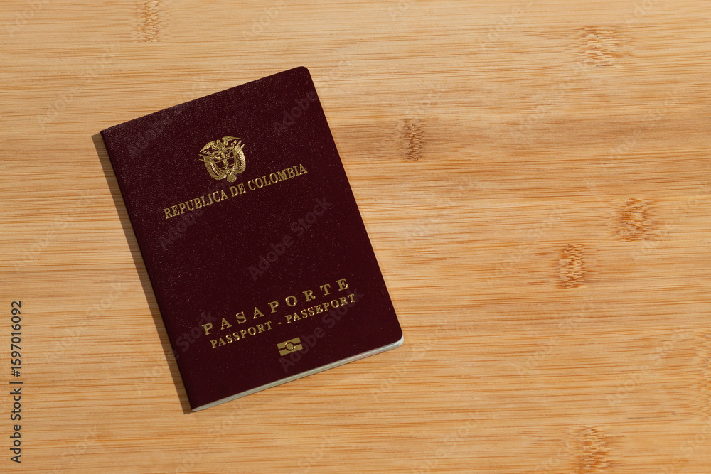 a Colombian Passport at the left over a wooden background a Colombian Passport at the left over a wooden background