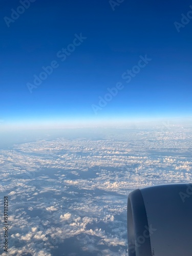 Photography view out of a plane window of clouds and a sunny blue sky