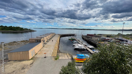  A working marina on the White Sea with small boats, colorful kayaks, and shipyard equipment under dramatic skies — a blend of northern industry and nature.
