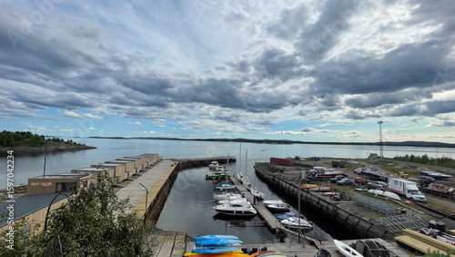  A working marina on the White Sea with small boats, colorful kayaks, and shipyard equipment under dramatic skies — a blend of northern industry and nature.
