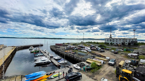 A working marina on the White Sea with small boats, colorful kayaks, and shipyard equipment under dramatic skies — a blend of northern industry and nature.