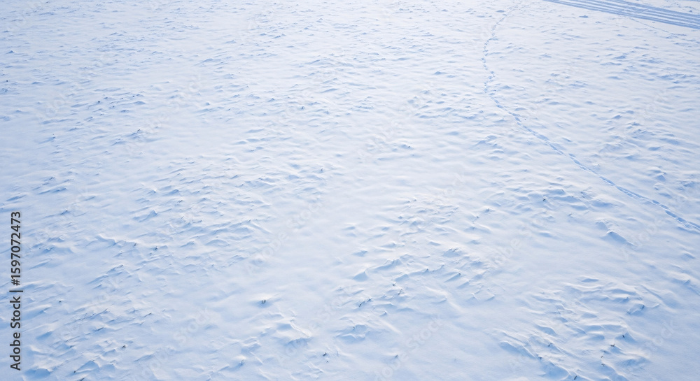 Fototapeta premium Smooth, undisturbed snow surface with subtle texture and faint tracks.