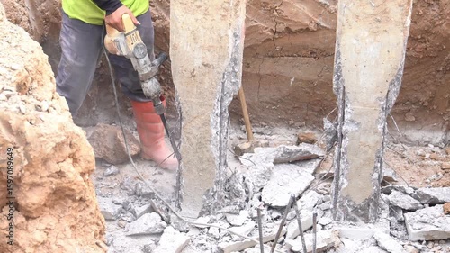A construction worker is operating a jackhammer to demolish the pile cap for foundation pouring.