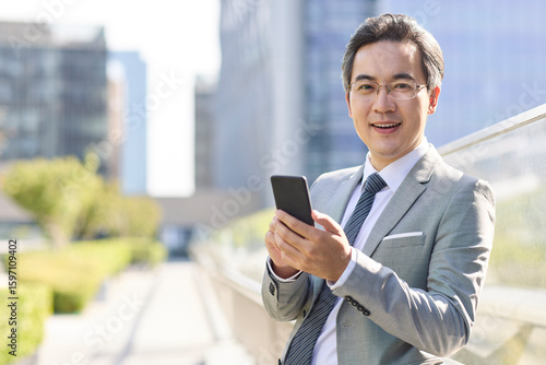 Mature businessman holding smart phone