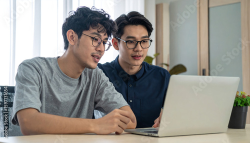 Two men discussing in front of a laptop