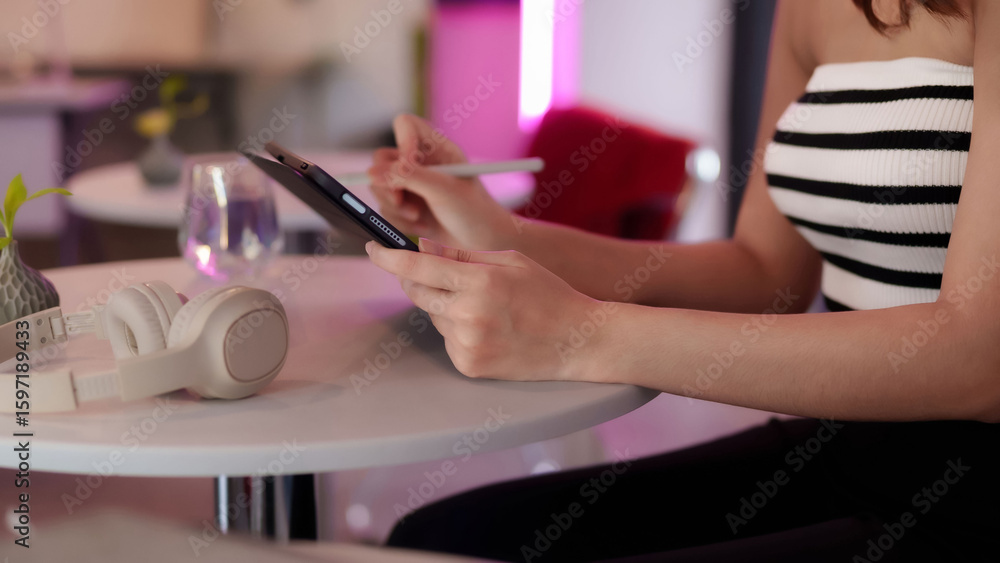 Fototapeta premium Asian adult woman freelancer using digital tablet stylus for creative work online at vibrant modern coworking space