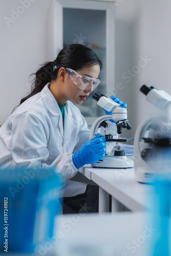 Scientist using microscope doing research in laboratory