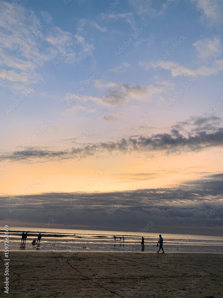 Dramatic Sunset Over Calm Sea with People Enjoying the Shoreline Dramatic Sunset Over Calm Sea with People Enjoying the Shoreline