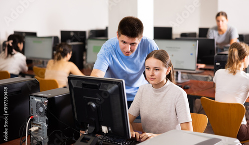 Bilde på lerret Smart interested teen schoolboy helping cute girl classmate sitting at computer