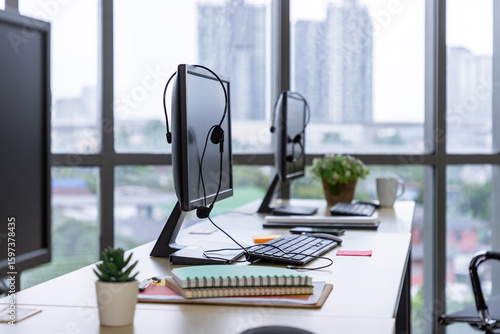 Call center desk with computer monitor, headset, keyboard, and office supplies