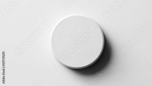 Single, white, round pill on a plain white surface