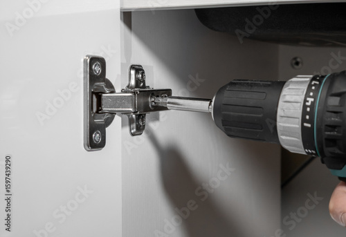 Quadro su tela Furniture assembly, screwing a screw into a cabinet door hinge close up