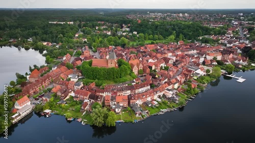 Aerial footage of Mölln the Eulenspiegel town with red rooftops, half-timbered houses and St. Nicolai church on  hill, surrounded by several small lakes.Camera moves slowly from right to left.