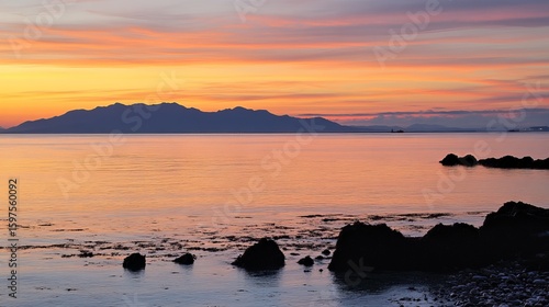 Calm waters meet a vibrant sunset over hills