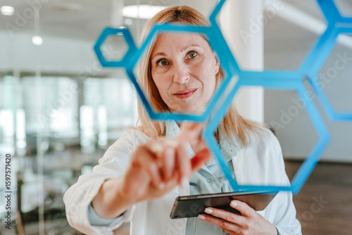 Engineer in laboratory examining molecular lattice with digital tablet