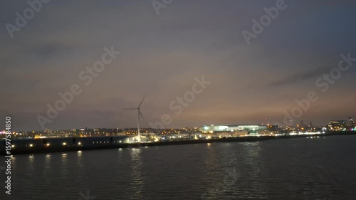 liverpool united kingome june 25 2024 Nighttime Waterfront View of Illuminated Cityscape With Wind Turbine Near Water