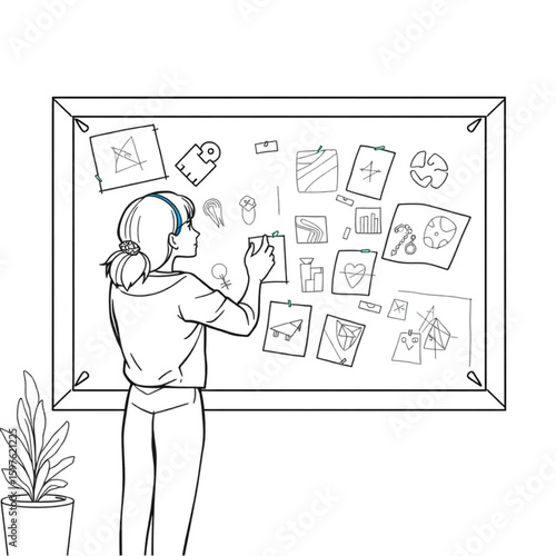 A design student pinning sketches to a corkboard in a studio