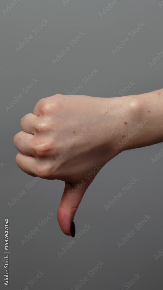 Close up isolated female hand showing like and dislike gesture raising thumb up then thumb down. Hand gestures. Approval dislike. Woman showing thumb up down isolated on gray copyspace background. Close up isolated female hand showing like and dislike gesture raising thumb up then thumb down. Hand gestures. Approval dislike. Woman showing thumb up down isolated on gray copyspace background.
