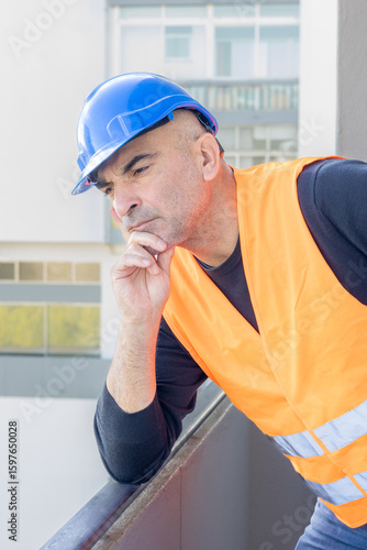 Portrait of an engineer wearing protective workwear posing looking at an unspecified point leaning chin on hand