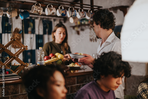 Photography A group of friends gathered in a homey kitchen environment, enjoying food and pleasant company, fostering warmth and camaraderie in a shared dining experience