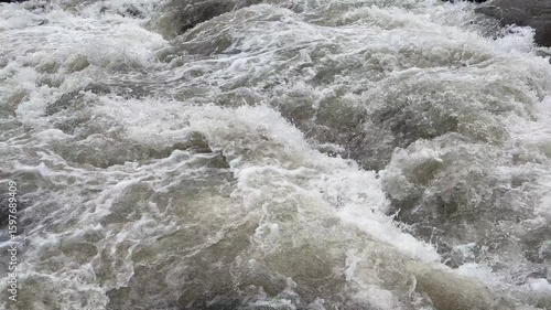Fast flowing mountain river with clear water rushing over large rocks and boulders. Clear and natural river water in the countryside. Scenic natural landscape in the countryside.
