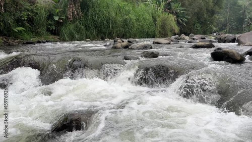 Fast flowing mountain river with clear water rushing over large rocks and boulders. Clear and natural river water in the countryside. Scenic natural landscape in the countryside.