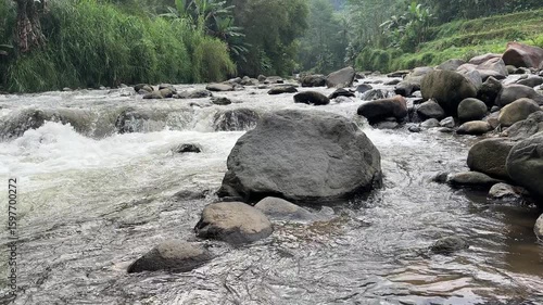 Fast flowing mountain river with clear water rushing over large rocks and boulders. Clear and natural river water in the countryside. Scenic natural landscape in the countryside.