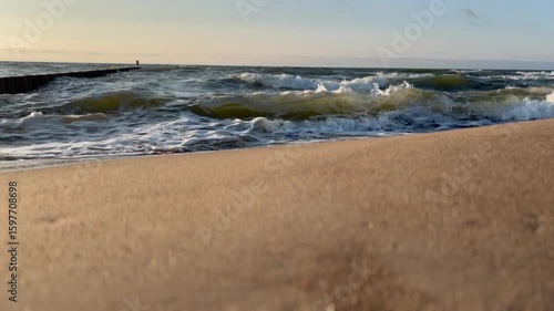 Golden sand beach with sea waves at sunset in Mielno, Baltic Sea coast, Poland
