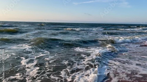Golden sand beach with sea waves at sunset in Mielno, Baltic Sea coast, Poland