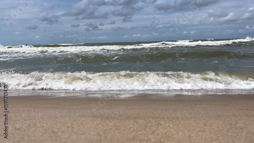 Golden sand beach with sea waves at sunset in Mielno, Baltic Sea coast, Poland