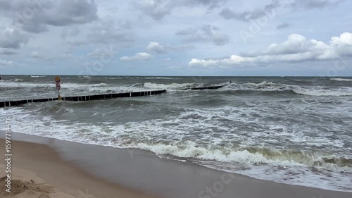 Cloudy day at the Baltic Sea, stormy waves and breakwater on the shore