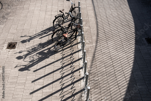 Minimalist bicycle lineup with long shadows in Copenhagen public space, Denmark, representing sustainable transport and morning light patterns in an urban ecological infrastructure setting