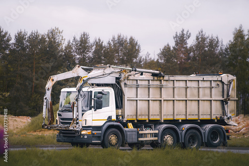 Fotografie Sanitation vehicle driving past dumpster containers