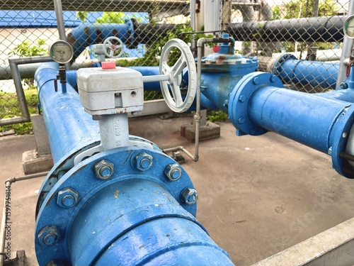 Foto Water pipeline system with blue-coated valves and pressure gauges in an outdoor industrial utility area, showing infrastructure and fluid control management