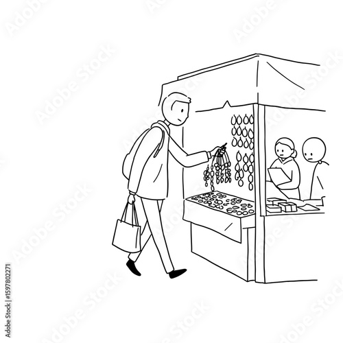 Man buying souvenirs at market stall while browsing merchandise  