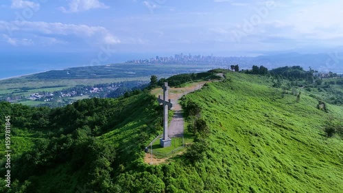 Large Hilltop Cross Facing Coastal City and Blue Sea on a Clear Sunny Day