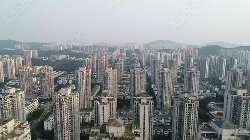 Wallpaper Mural A dense urban sprawl under a hazy sky, featuring tightly packed, tall buildings receding into the distance, with distant hills visible Torontodigital.ca