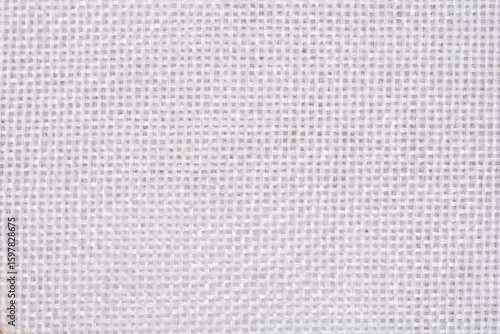 A close-up of white tapestry fabric texture with a visible square weave pattern