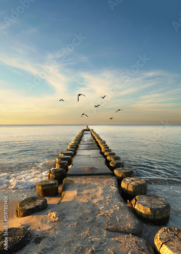 Fototapeta Naklejka Na Ścianę i Meble -  Idyllic Autumn Sunset Over the Baltic Sea with a Weathered Wooden Groyne and Tranquil Coastal Scenery