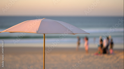 Wallpaper Mural Sunny beach with gentle waves and a single umbrella under warm golden hour light. Torontodigital.ca
