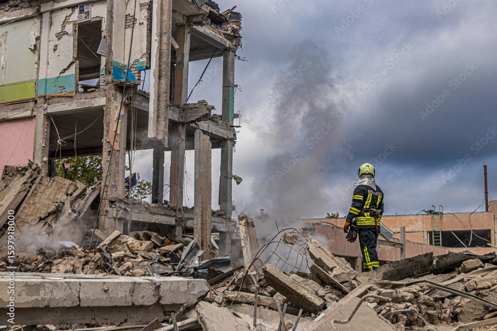 Fototapeta premium Firefighter standing on ruins of missile-struck building