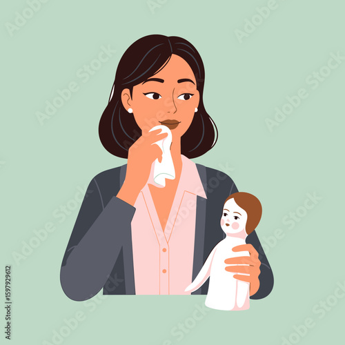Woman in a blazer wiping her face with a tissue while holding a doll in her arms, looking thoughtfully to the side.