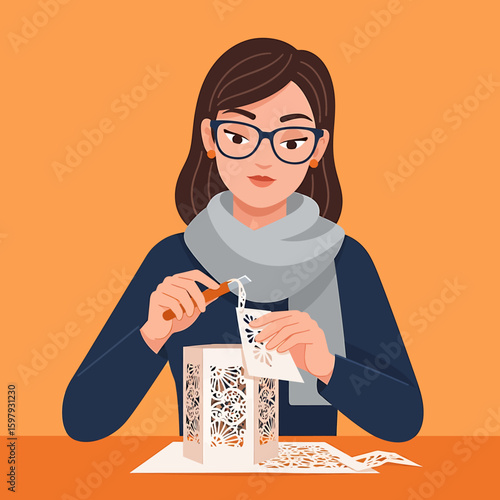 Woman with glasses carefully removes paper scraps from a decorative, laser-cut paper lantern, working at a table.