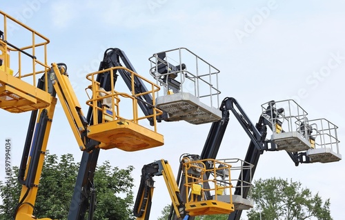 Wallpaper Mural Group of black and yellow aerial platforms of cherry pickers against cloudy sky  Torontodigital.ca