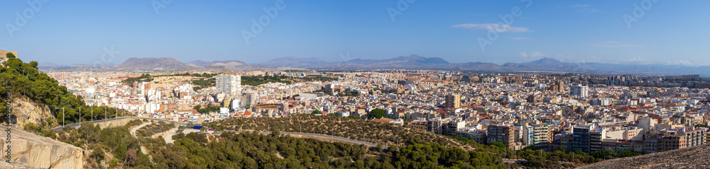 Panoramic view of Alicante, Spain, showcasing a vibrant cityscape with residential and commercial buildings, surrounded by hills and mountains under a clear blue sky. Panoramic view of Alicante, Spain, showcasing a vibrant cityscape with residential and commercial buildings, surrounded by hills and mountains under a clear blue sky.
