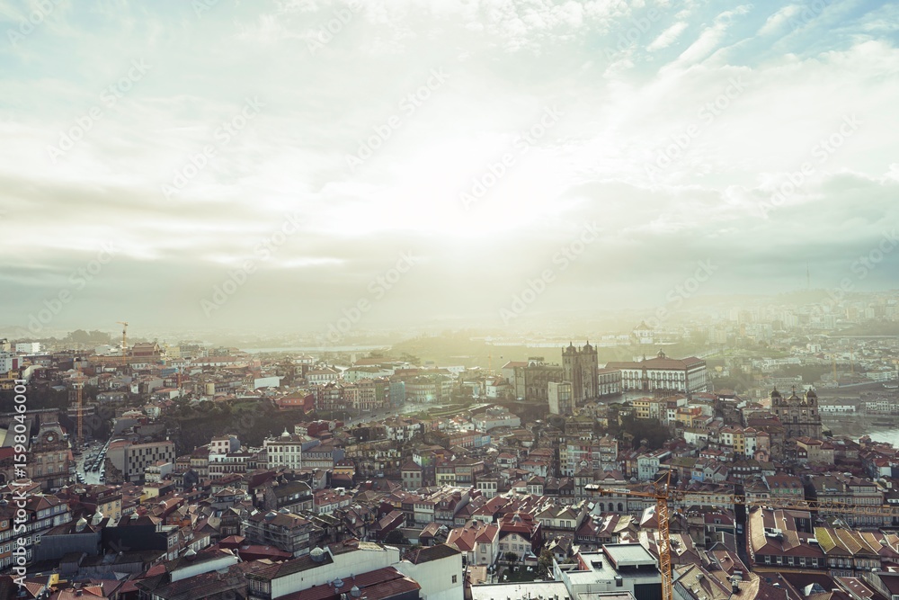 Obraz premium Sunrise bathes Porto in a warm glow. Diverse architecture, including notable cathedrals and traditional buildings, come together in a captivating urban panorama
