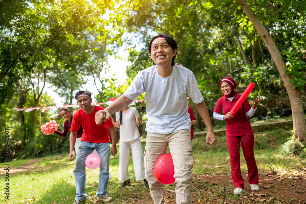 Fototapeta premium Portrait of an Indonesian southeast asian people celebrate Indonesia Independence Day on the 17th of August with a game of keep the balloon from blowing out outdoors. Concept of Kemerdekaan Indonesia