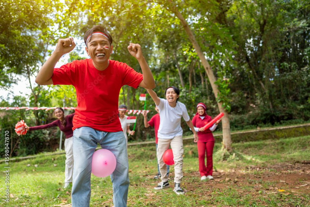 Obraz premium Portrait of an Indonesian southeast asian people celebrate Indonesia Independence Day on the 17th of August with a game of keep the balloon from blowing out outdoors. Concept of Kemerdekaan Indonesia